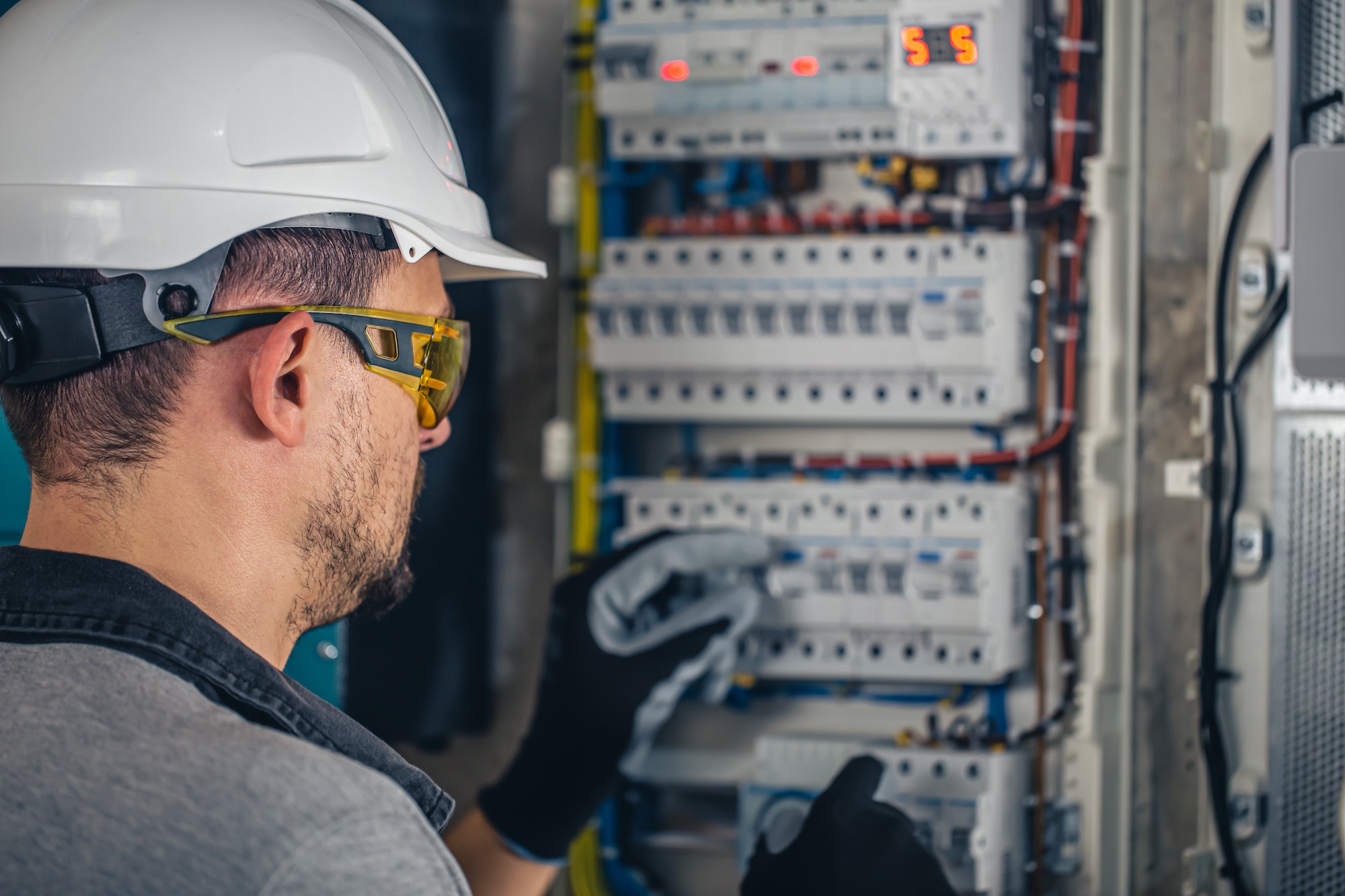 Man, an electrical technician working in a switchboard with fuses.